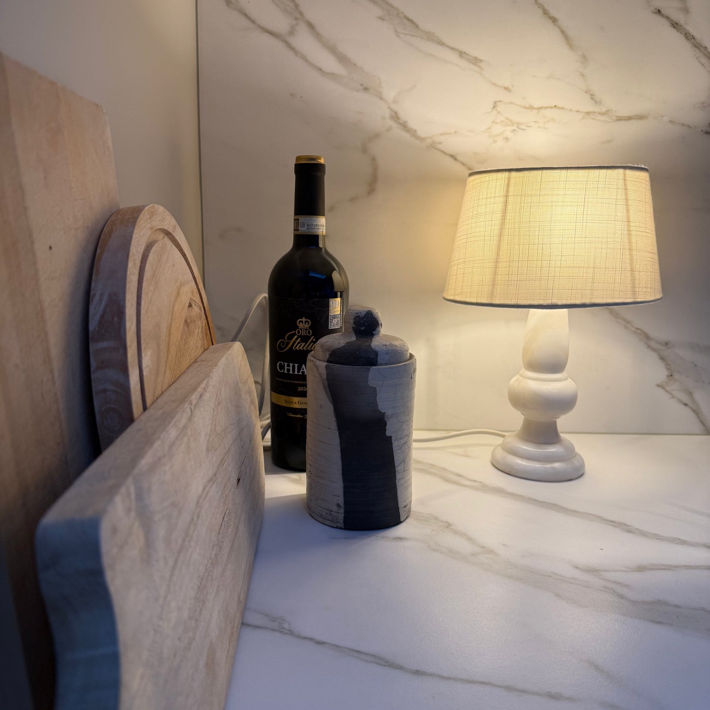 Vintage keramiek pot met deksel in Raku-stijl naast houten snijplanken en een vintage tafellampje