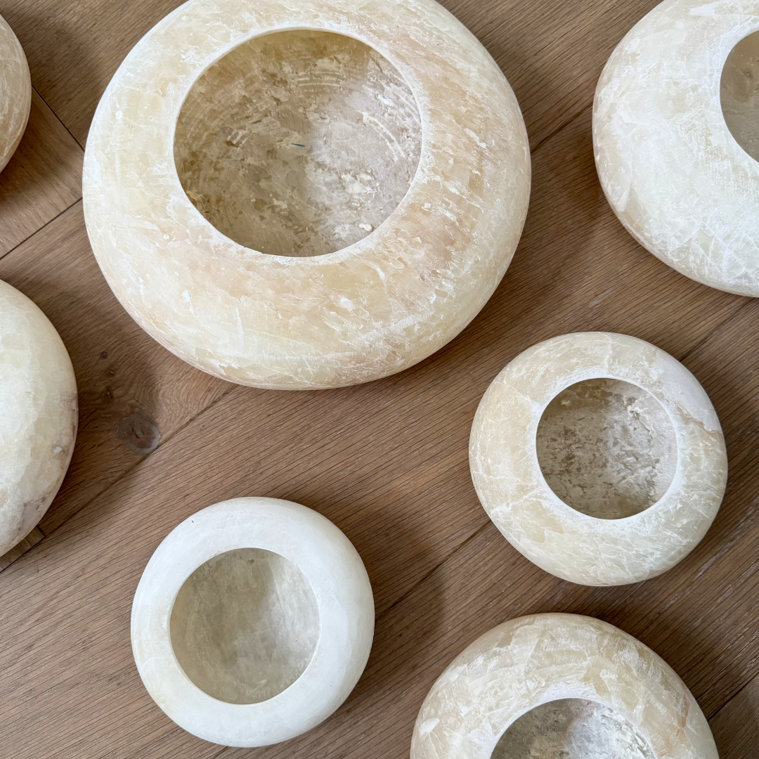 Groep alabaster Pebble waxinelichthouders in warm witte tinten op een eikenhouten ondergrond