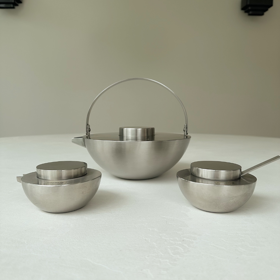 Blomus Asia Theeset: RVS theepot, suikerpot en melkkan  (vintage) neergezet op een witte tafel tegen een neutral achergrond
