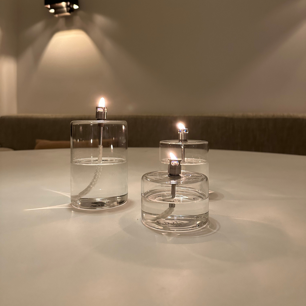 Set van 3 cilindervormige transparant glazen olielampen van Peri Living met brandende vlam in een rustgevende sfeervolle interieursetting