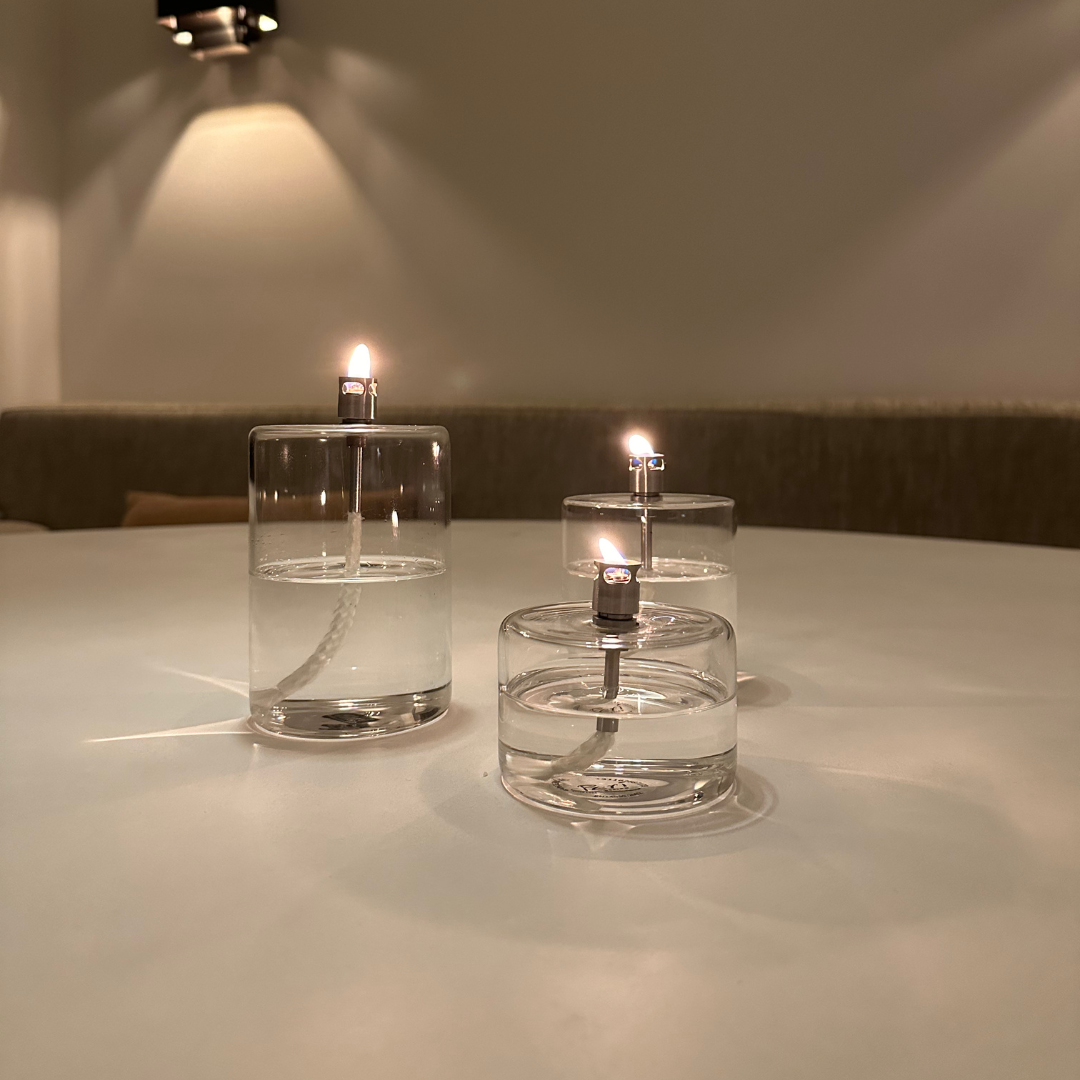 Set van 3 cilindervormige transparant glazen olielampen van Peri Living met brandende vlam in een rustgevende sfeervolle interieursetting