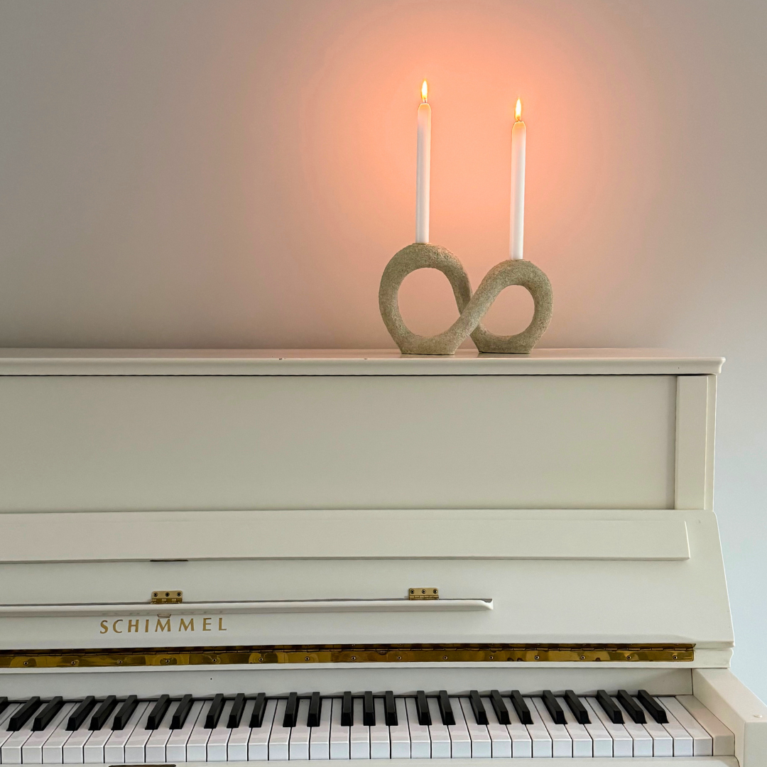 Gedraaide kaarshouder Dacian met twee brandende kaarsen op een witte piane