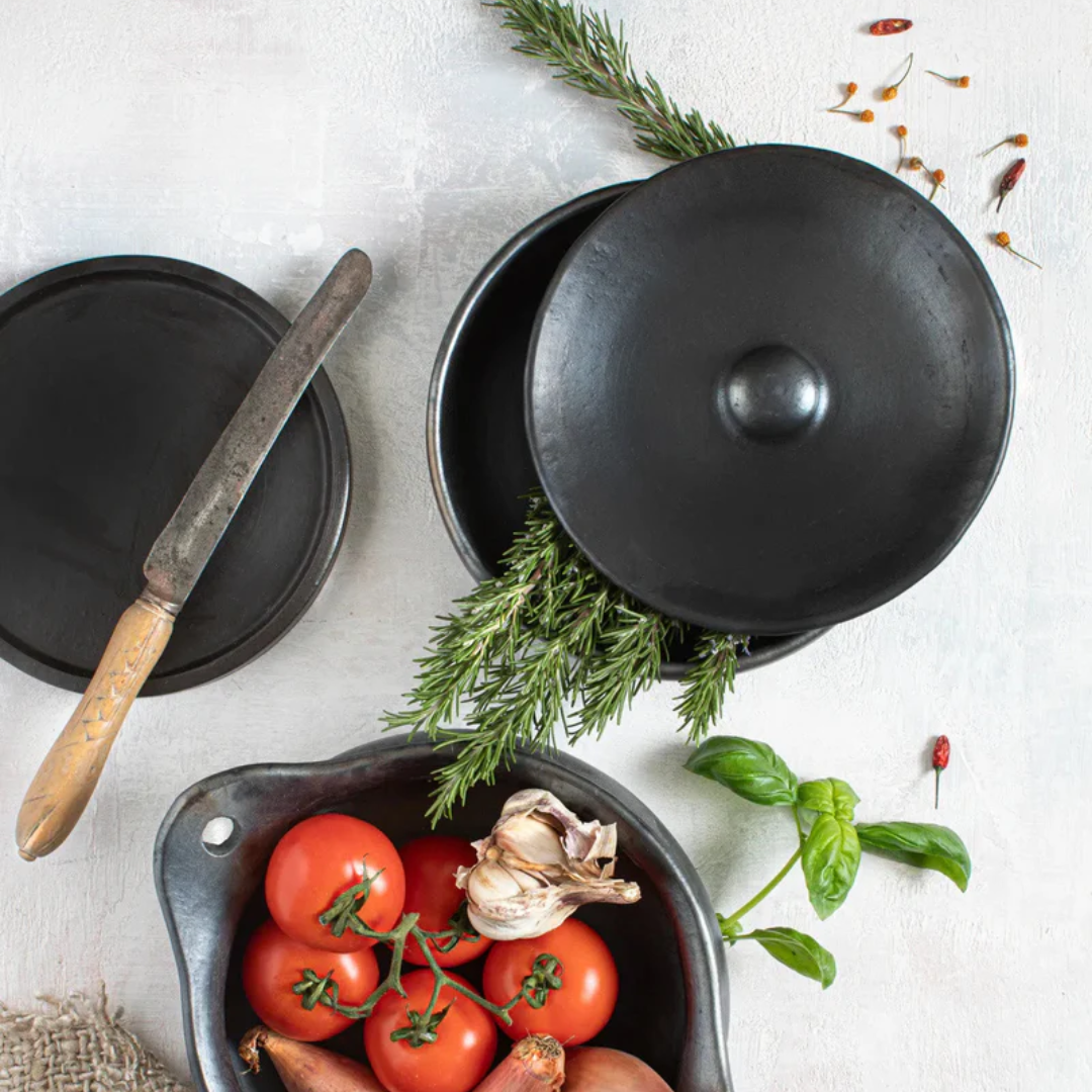 Handgemaakte pot van Bazar Bizar op een wit oppervlak, samen met ander servies uit de Burned collectie van Bazar Bizar.