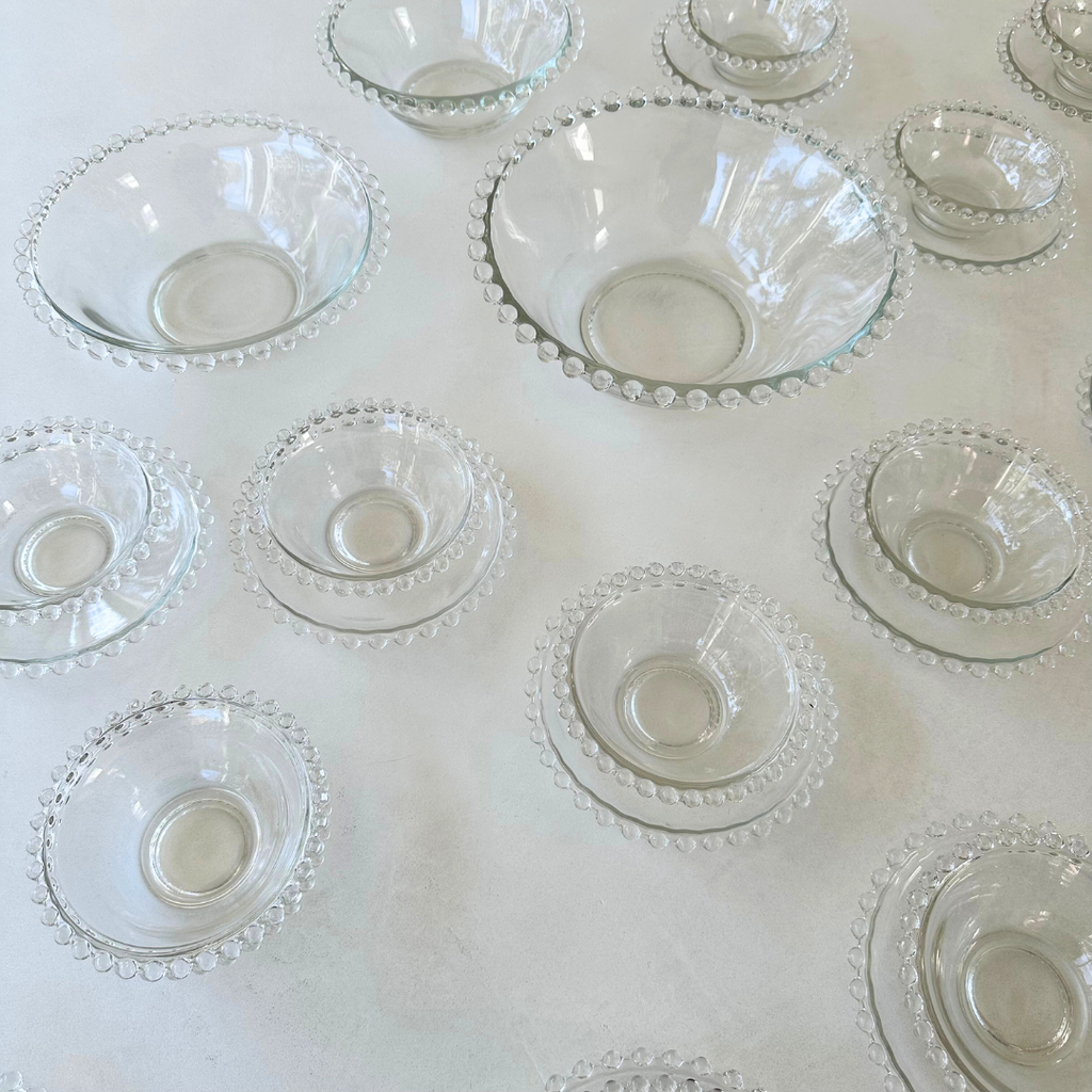 Bovenaanzicht van de schaaltjes en schoteltjes met focus op de symmetrie en helderheid van het glas en de bolletjesrand
