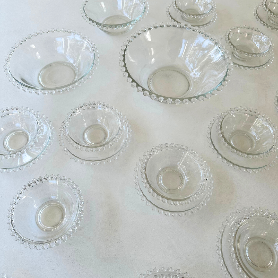 Bovenaanzicht van de schaaltjes en schoteltjes met focus op de symmetrie en helderheid van het glas en de bolletjesrand