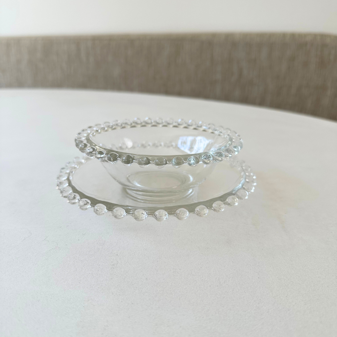 Zijaanzicht van het heldere glazen schaaltje en schotel met decoratieve bolletjesrand