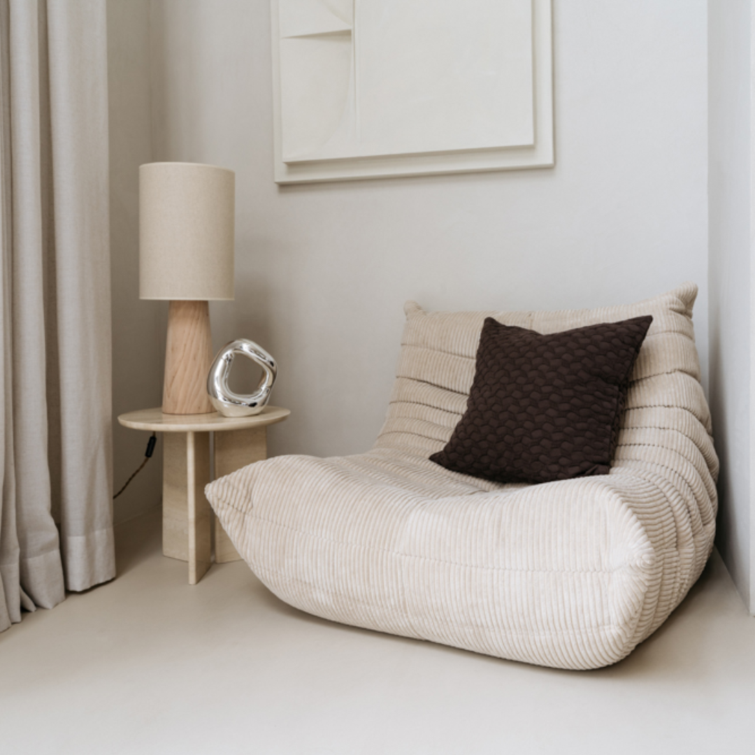 Ella kussenhoes gestyled op een neutrale fauteuil in een modern minimalistisch interieur.