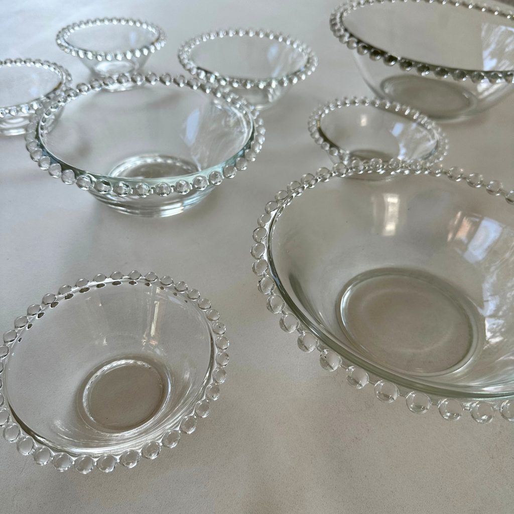 Transparante schalen in diverse formaten met vintage uitstraling en bolletjesdecoratie, gefotografeerd tegen een neutrale achtergrond

