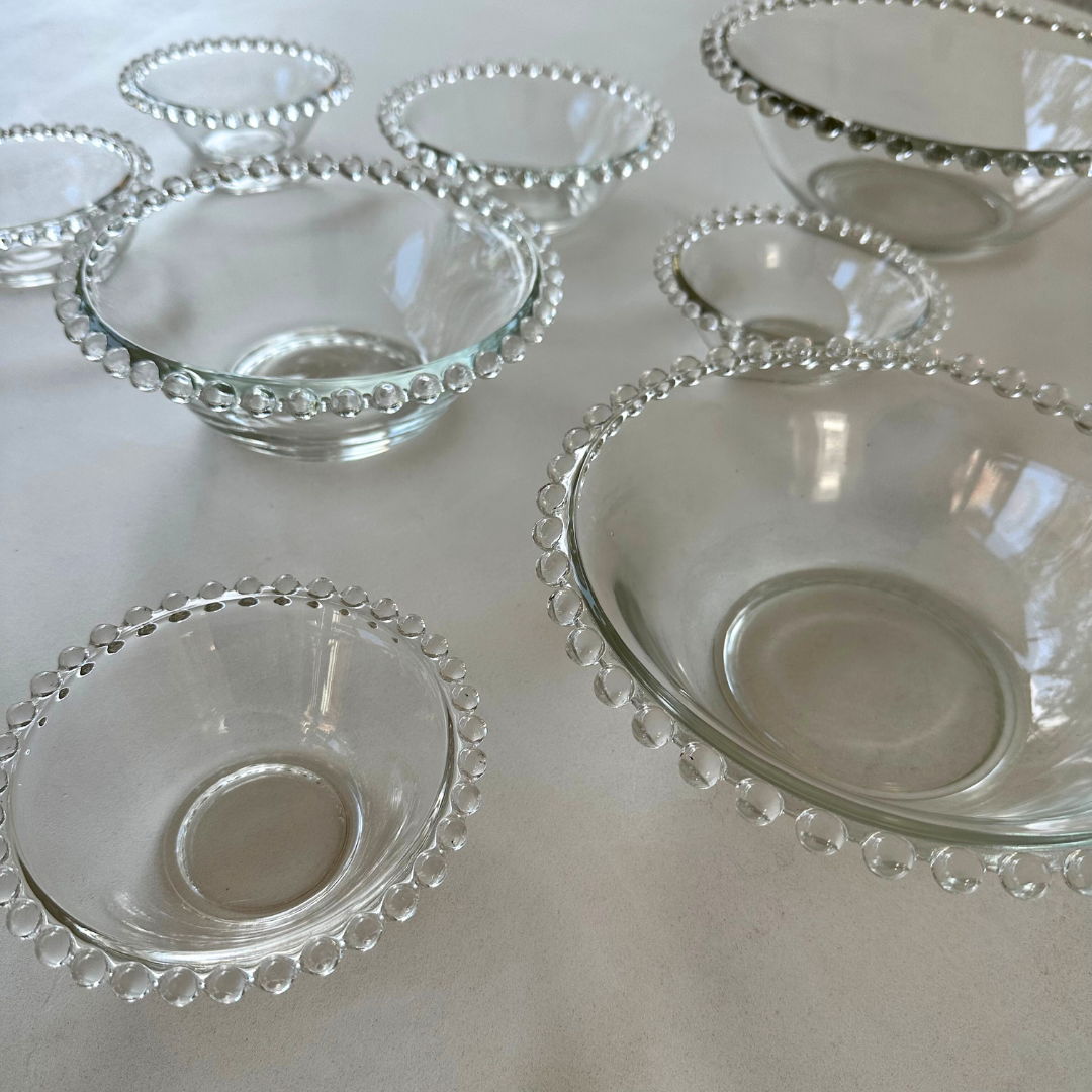 Transparante schalen in diverse formaten met vintage uitstraling en bolletjesdecoratie, gefotografeerd tegen een neutrale achtergrond


