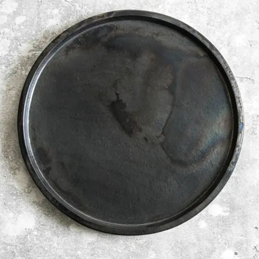 Groot rond bord van terracotta in diepe zwarte tint – modern en rustiek serviesdesign