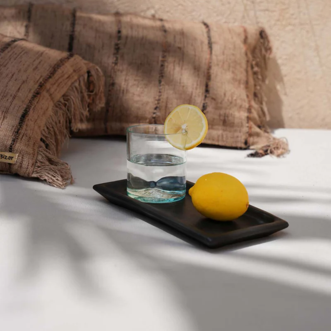 Handgemaakt keramisch sushi bord van Bazar Bizar met een glas water en citroen, boho styling.