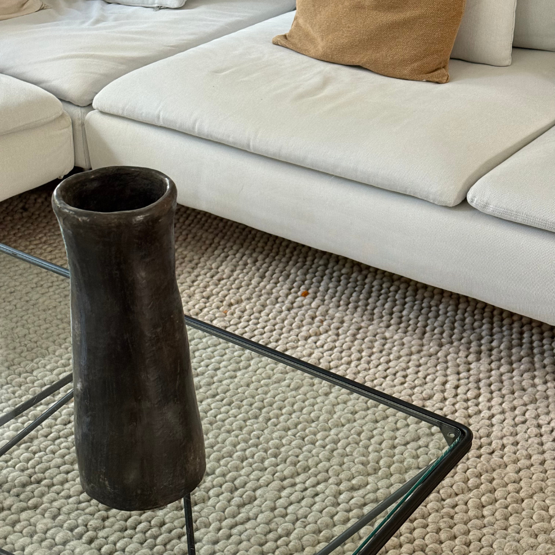 Zwarte handgemaakte Idris van 100% faretrade klei op een glazen tafel, warm interieurdetail