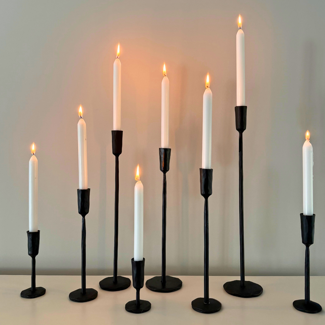Verschillende formaten zwart metalen kaarshouders met witte brandende kaarsen
