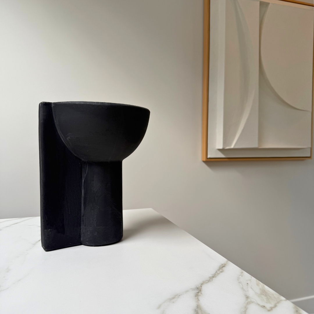 Sculpturale mat zwarte terracotta vaas Lisa van SelectedBy met op de achtergrond een kunstwerk van Art In Return