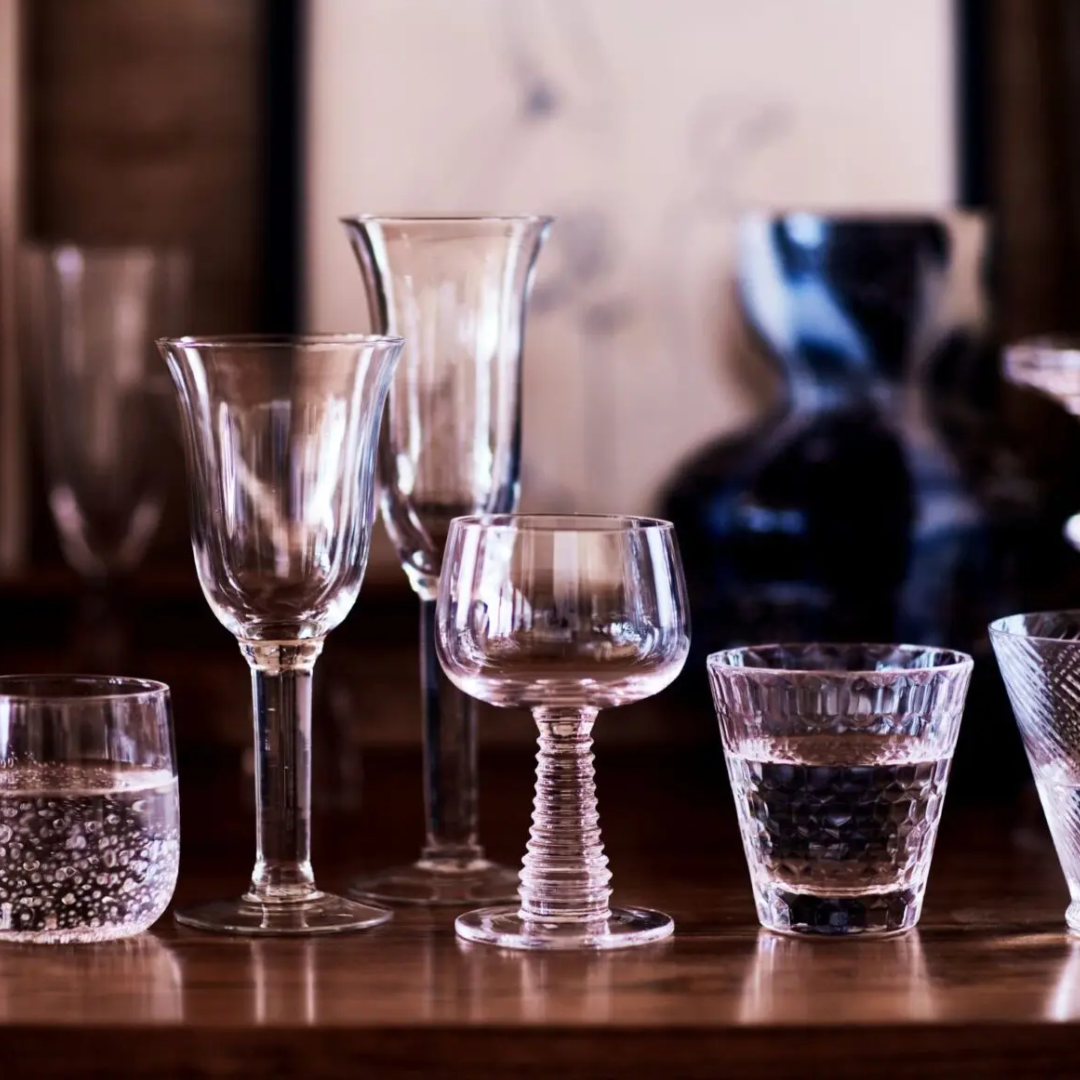 Lou wijnglas met geribbelde voet temidden van een aantal andere decoratieve glazen op een houten tafel