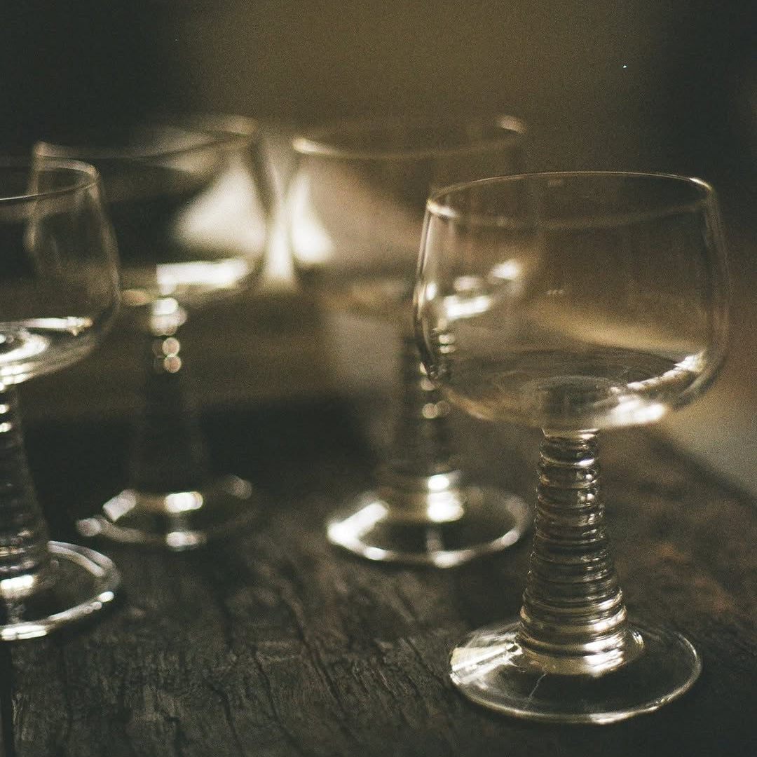 4 wijnglazen met transparant geribbelde voet op een houten tafel