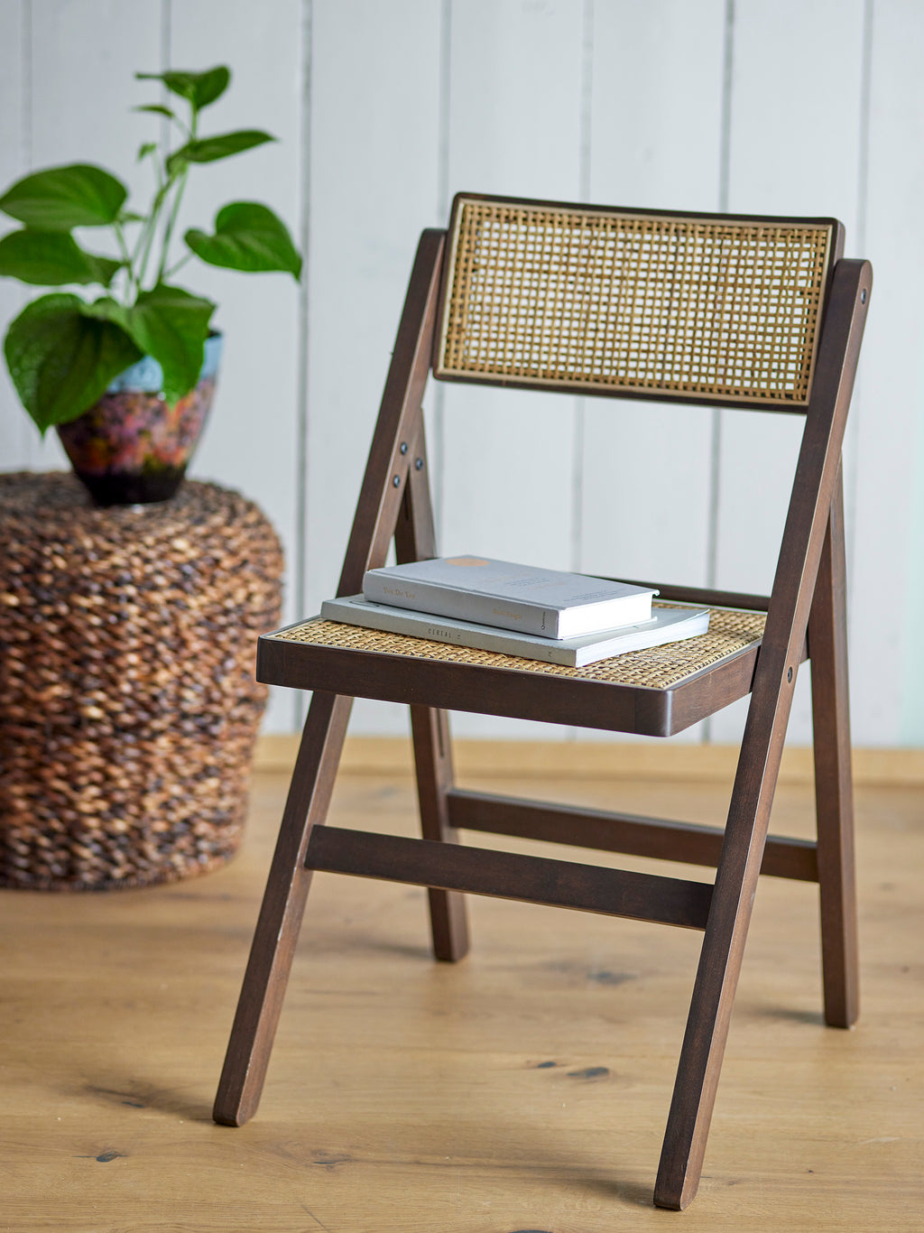 De Loupe stoel in een neutraal interieur met een stapel boeken op de zitting