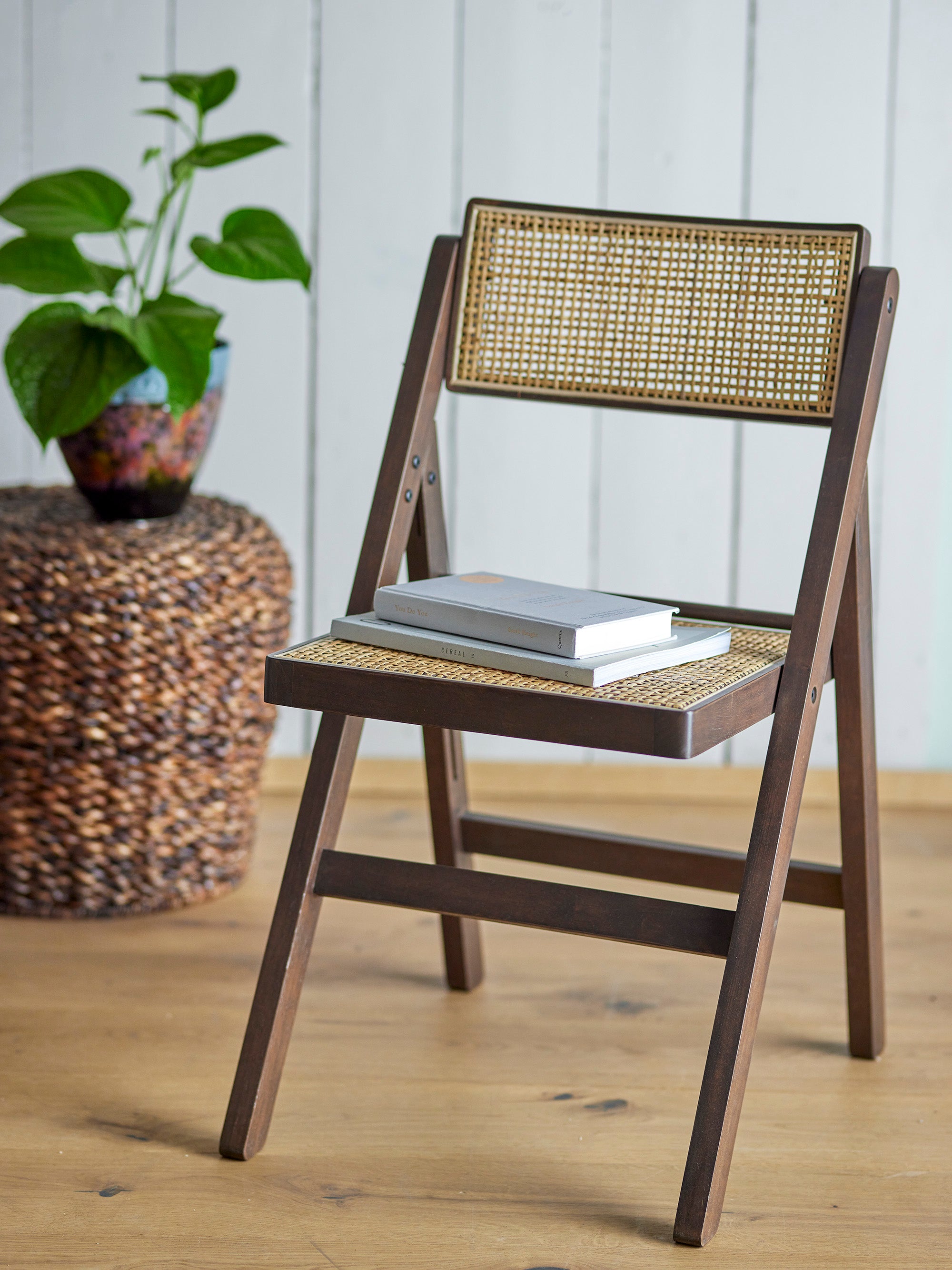 De Loupe stoel in een neutraal interieur met een stapel boeken op de zitting