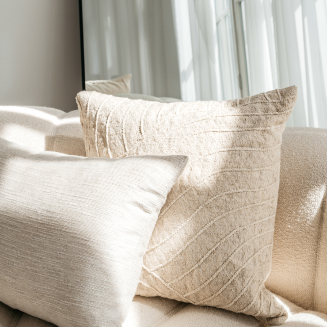 Lynn kussenhoes ggecombineerd met een ander naturel kussen op een neutrale bank in een wit interieur.