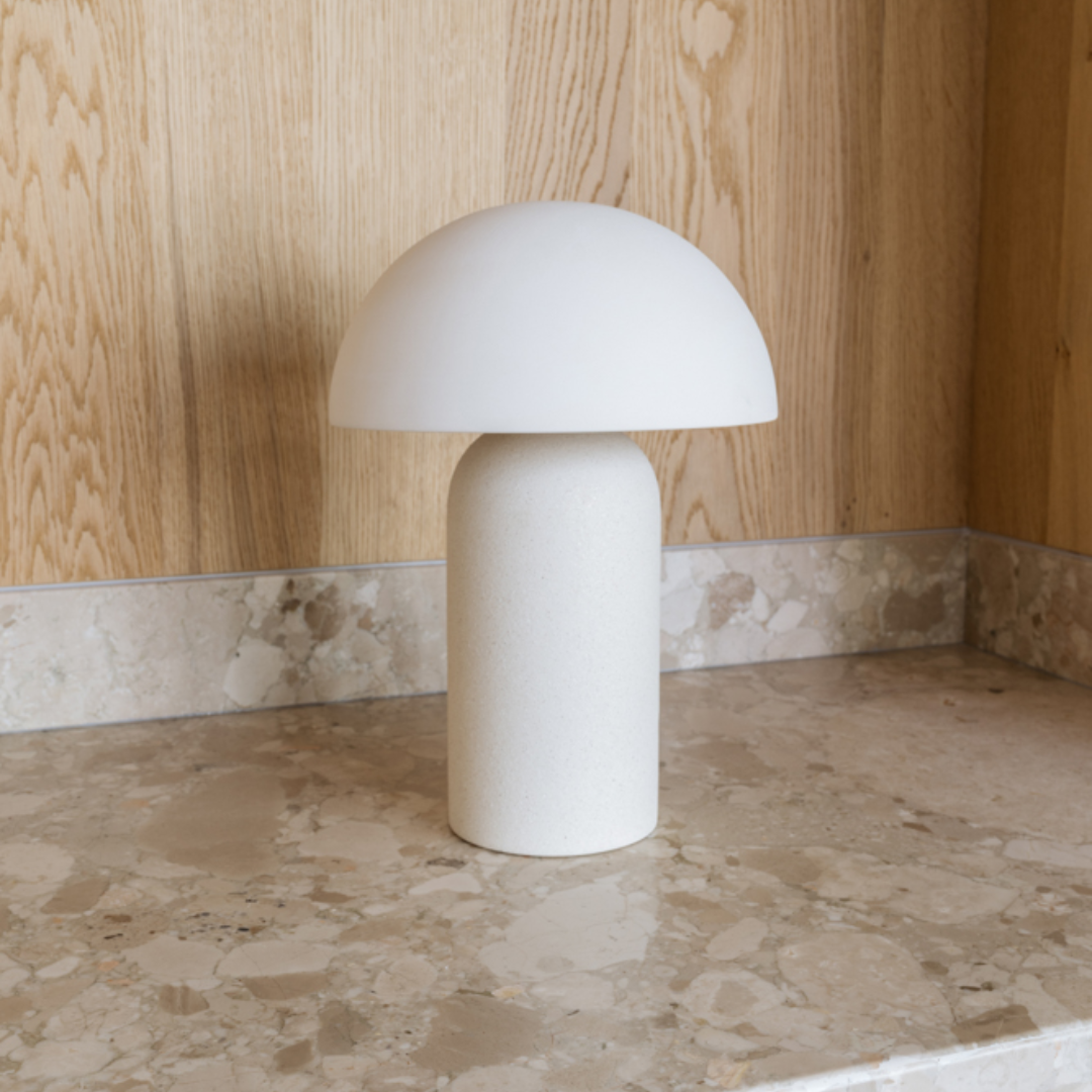 De handgemaakte keramieken Maeve tafellamp een beige natuurstenen werkblad voor een houten achterwand 