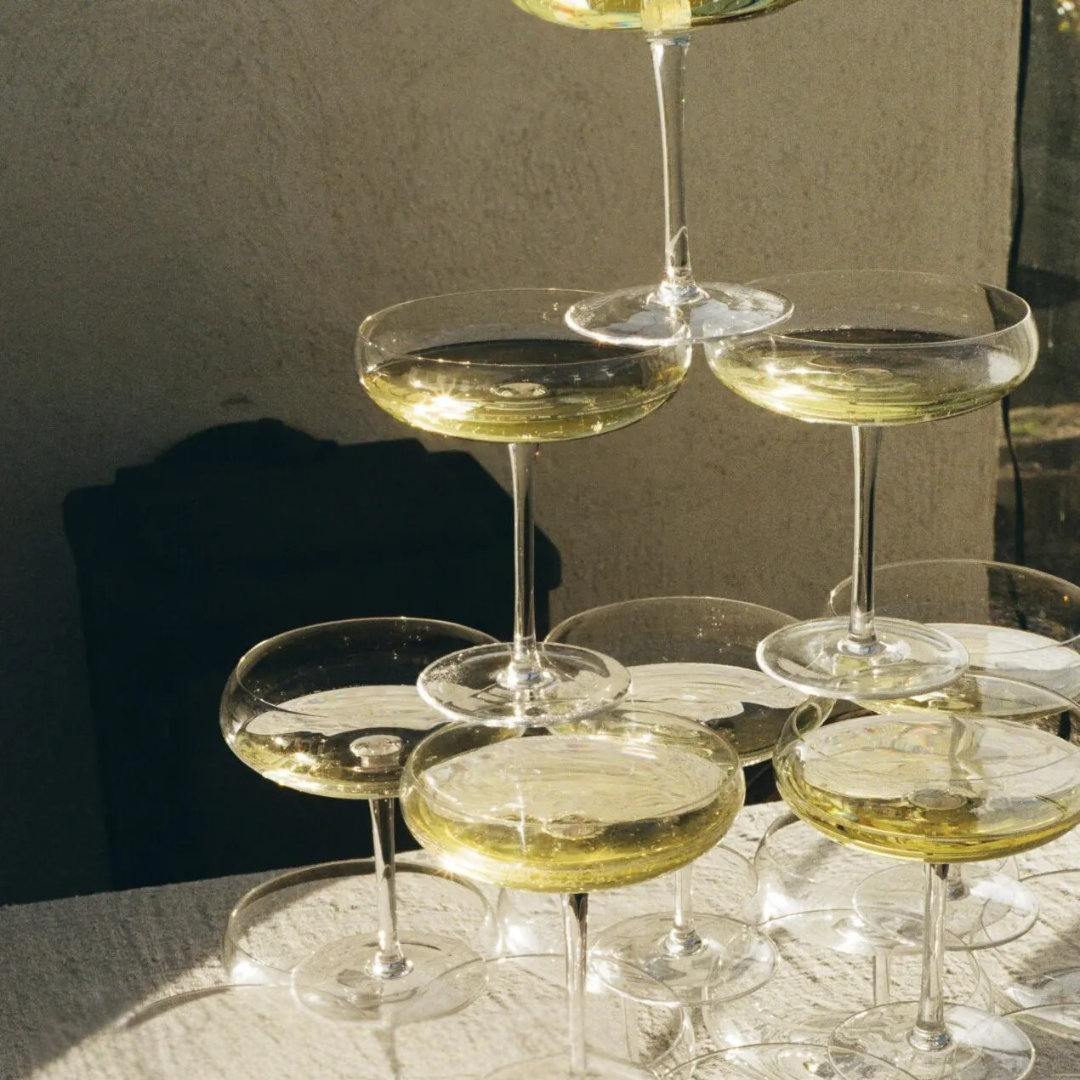 Met champagne gevulde Mimosa glazen van Olsson & Jensen op elkaar gestapeld in piramidevorm