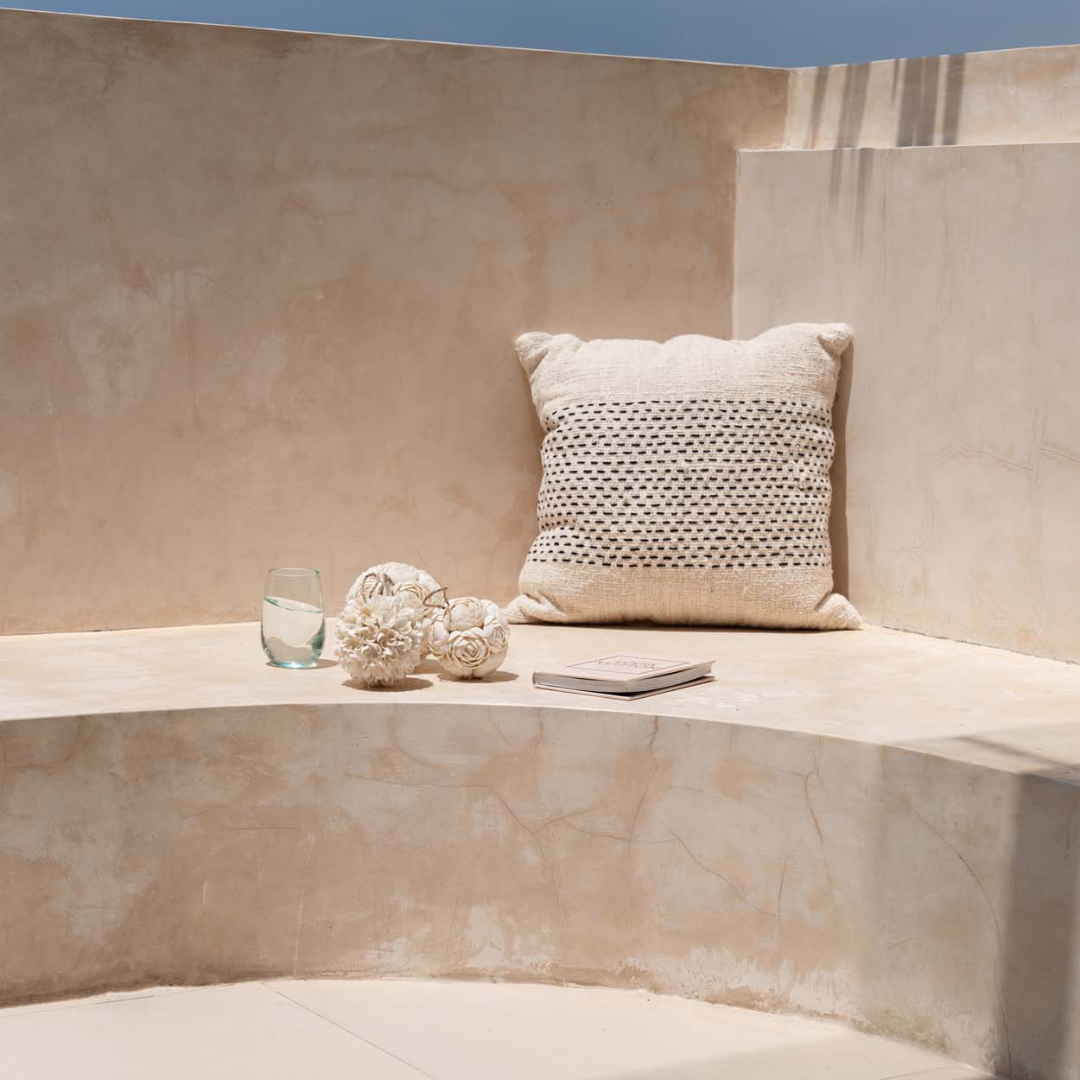Misty kussenhoes als decoratief accent op een neutrale bank op een zonovergoten terras