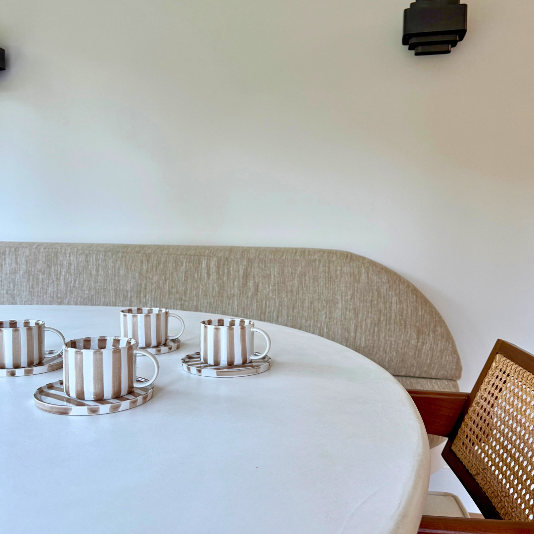 Monica kop en schotel van beige / wit gestreept handgeschilderd keramiek op witte tafel – sfeervol koffiemoment met karakter