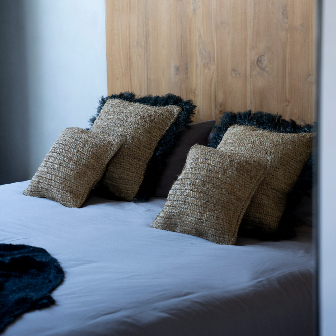 Twee Raffia Flores Kussenhoezen gecombineerd met 2 grotere raffia kussens met zwarte franjerand op een opgemaakt bed