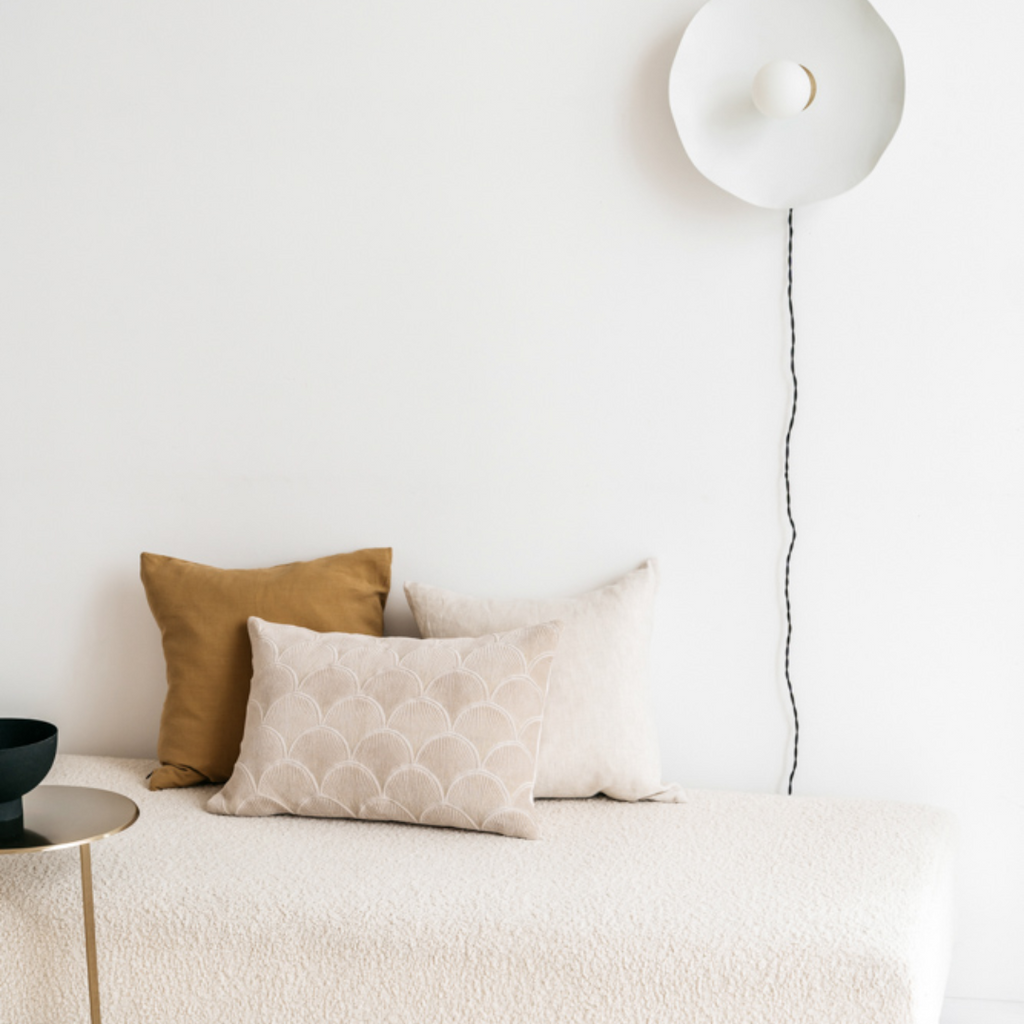 Scotty linnen kussenhoes in goudbruine tint gestyled op een ecru bank in een minimalistisch interieur