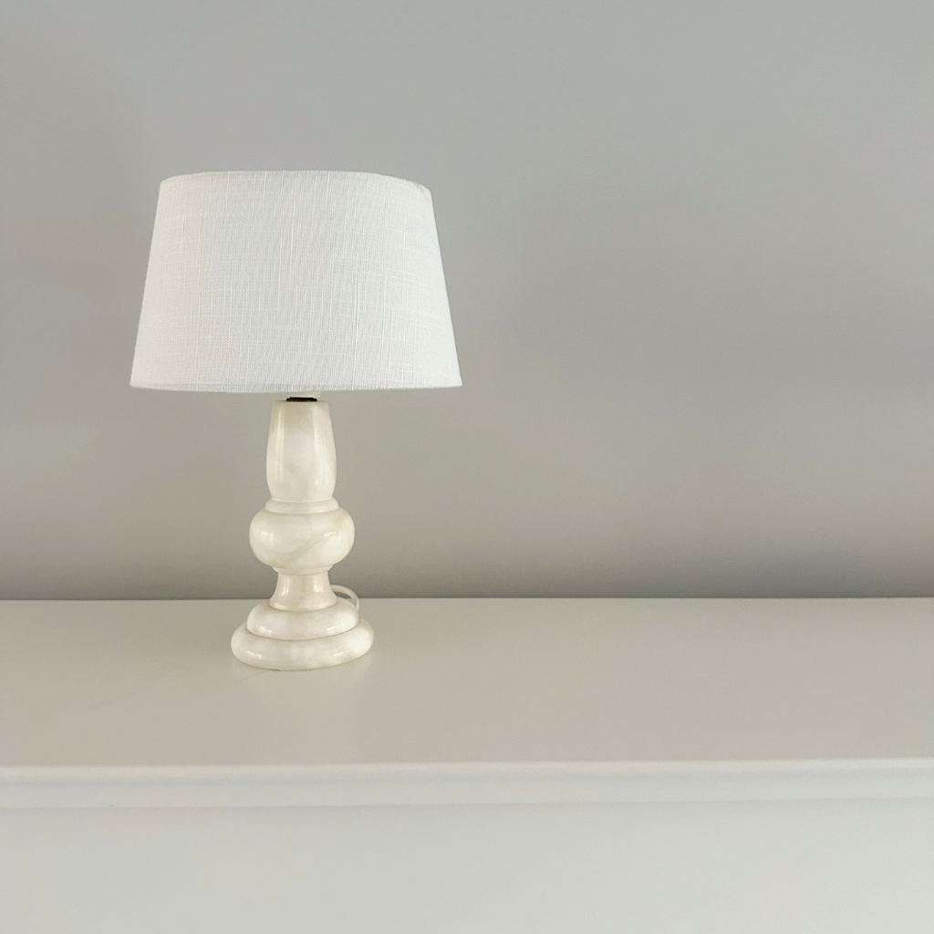 Wit marmeren vintage tafellamp met wit stoffen kap in een minimalistische setting met neutrale kleuren