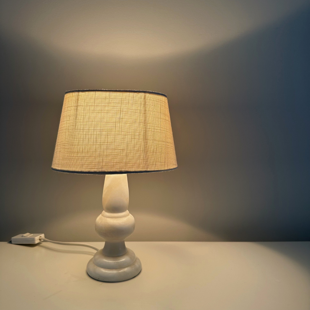 De vintage marmeren tafellamp met sfeervol licht dat schijnt door de witte stoffen kap