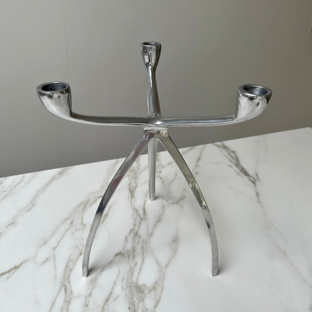 Tripod kandelaar op een marmeren oppervlak met reflectie van het licht