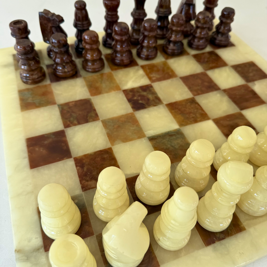 Detail van natuurstenen schaakset; albasten schaakbord met handgesneden onyx schaakstukken in bruin en wittinten