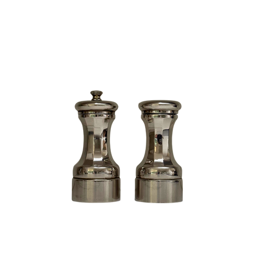 Vintage peper- en zoutstel van zilverkleurig metaal met getailleerde vormen, vrijstaand gefotografeerd.