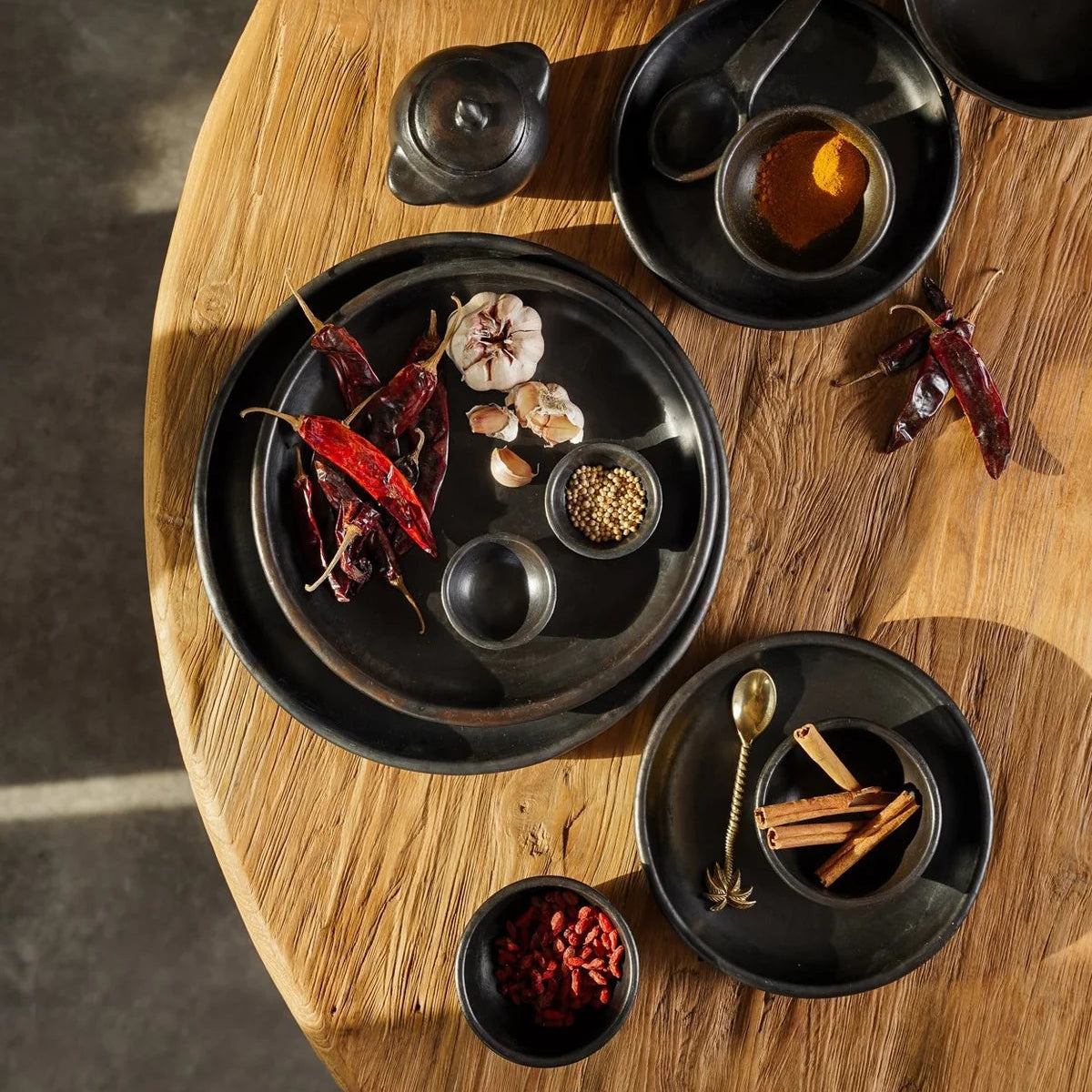 Diverse kommen en borden uit de Burned servies collectie van Bazar Bizar gestyled op een houten tafel